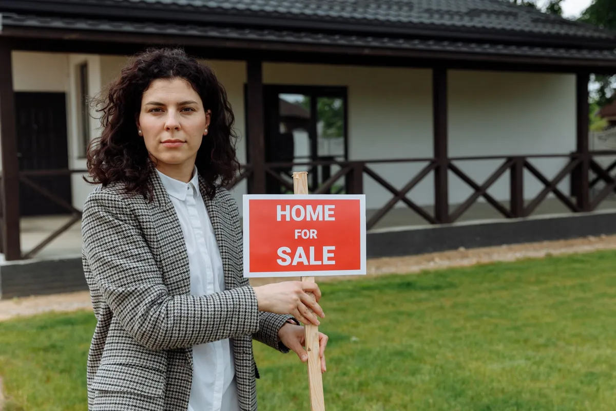 A real estate sign stands in front of a house, symbolizing the process of selling a home quickly.
