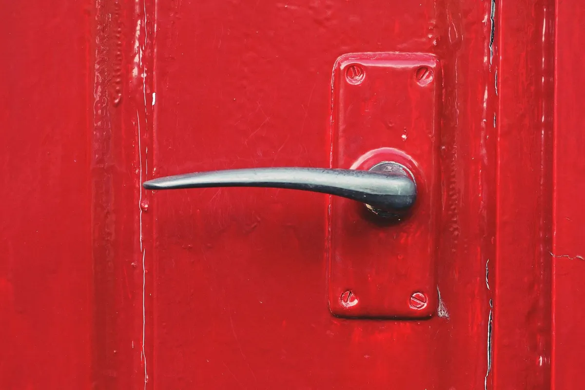 A bright red door with a metallic handle, symbolizing new beginnings in selling a house.