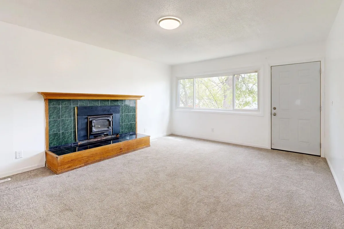 Bright empty living room with a modern fireplace and large window, reflecting the appeal of quick home sales.
